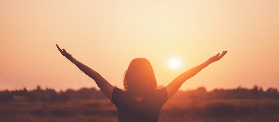 Freedom feel good and summer vacation adventure concept. Copy space of woman raise hand up standing at rice field and morning sky abstract background. Vintage tone filter effect color style.