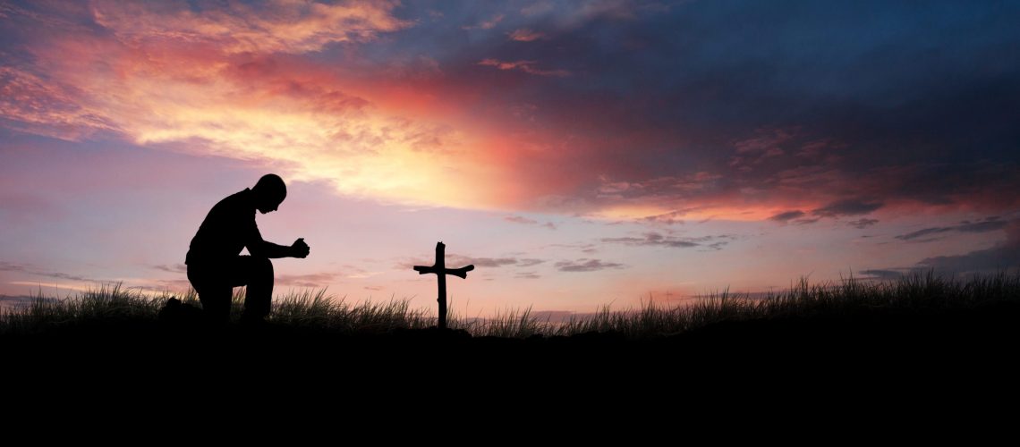 Man praying over a cross and grave