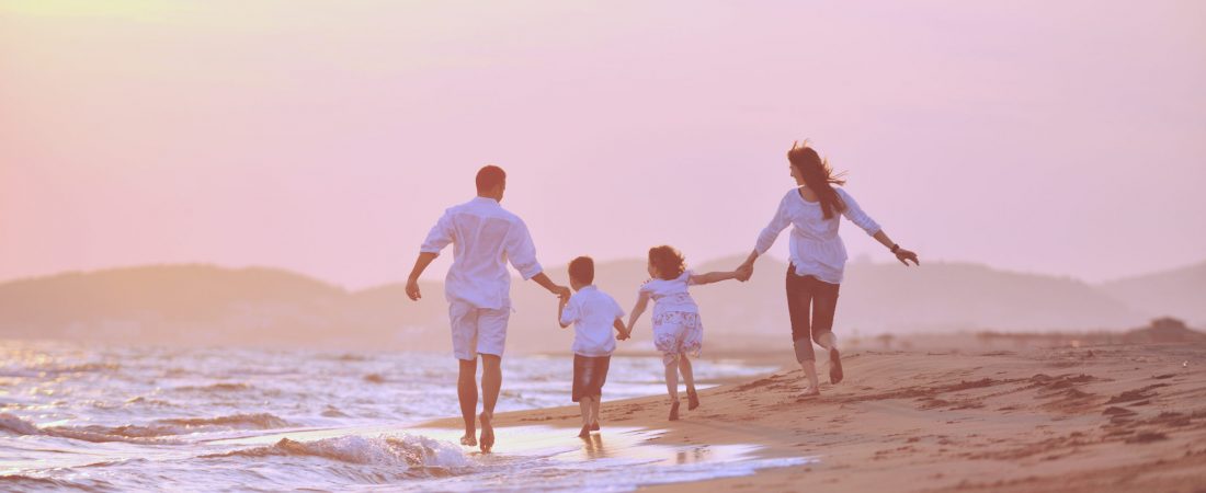 Happy young family have fun on beach run and jump  at sunset