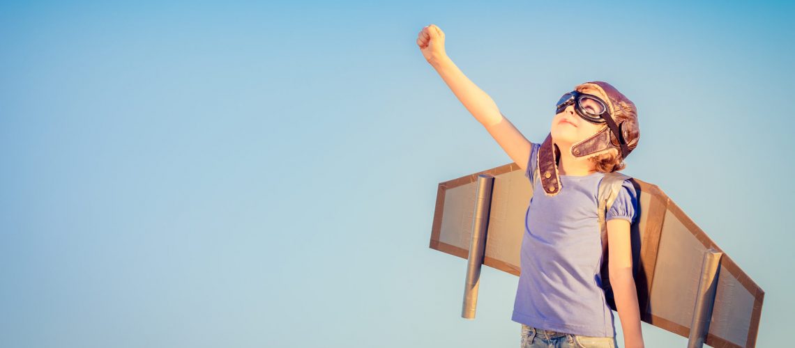 Happy child playing with toy wings against summer sky background