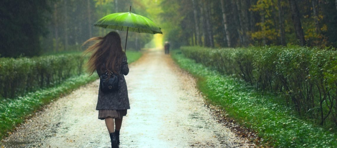 beautiful girl walking under rainfall in autumn park